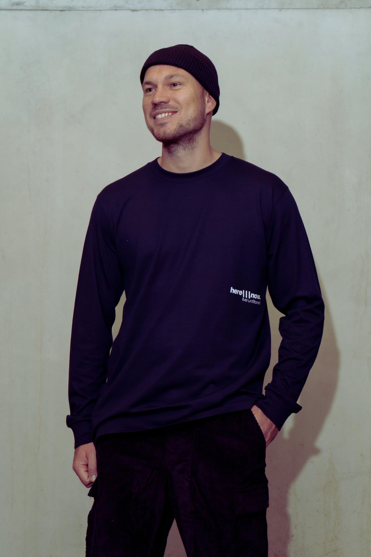 Man wearing a dark long-sleeve shirt with a logo against a plain background